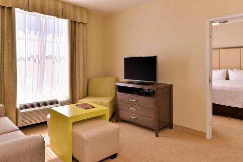 a hotel room with a television and a bedroom at Homewood Suites by Hilton Houma in Houma