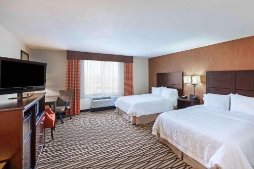 a hotel room with two beds and a flat screen tv at Hampton Inn & Suites Morgan City in Morgan City