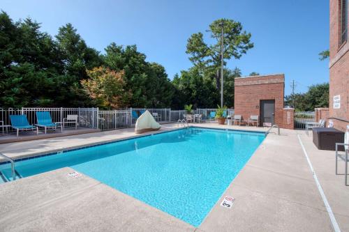 einem Pool mit blauen Stühlen und einem Backsteingebäude in der Unterkunft Hampton Inn Wilmington University Area in Wilmington