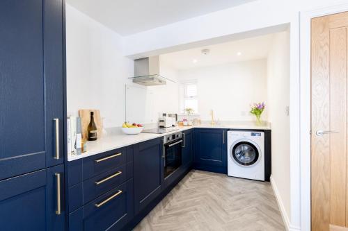 a kitchen with blue cabinets and a washing machine at CRINGLE COTTAGE, The Lanes Cottages, Stokesley in Stokesley