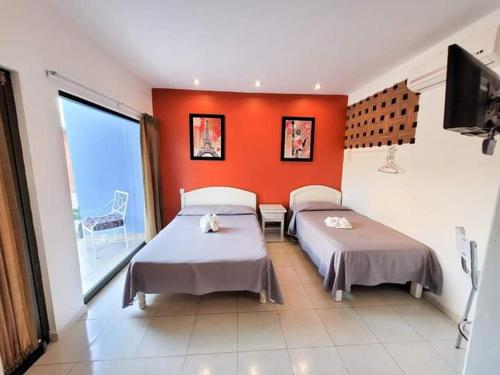 a bedroom with two beds and an orange wall at HOTEL OBREGON in Iguala de la Independencia