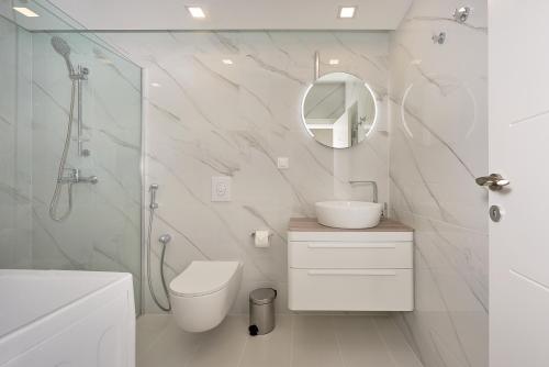 La salle de bains est pourvue de toilettes, d'un lavabo et d'un miroir. dans l'établissement Georgiy Lux Apartments, à Lastva