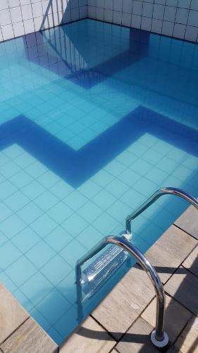 a large blue swimming pool with a water facet at Dom Pedro 54 in Guarujá