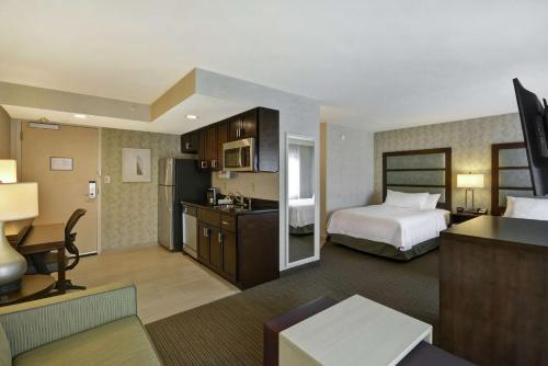 a hotel room with a bed and a kitchen at Homewood Suites by Hilton Indianapolis Carmel in Carmel