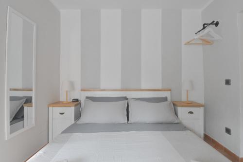 ein weißes Schlafzimmer mit einem großen Bett mit zwei Nachttischen in der Unterkunft Baceno Room in Baceno