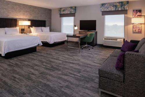 ウィンストン・セーラムにあるHampton Inn & Suites Winston-Salem Downtownのベッド2台とソファが備わるホテルルームです。
