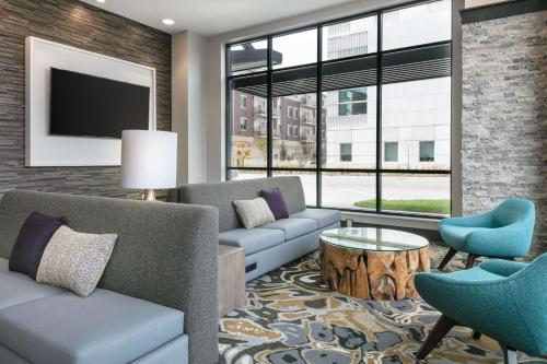 a living room with a couch and chairs and a tv at Hilton Garden Inn Iowa City Downtown University in Iowa City