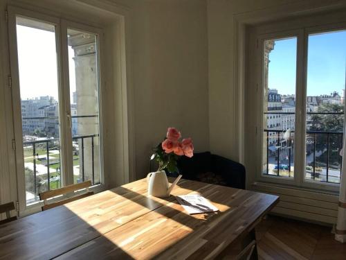 une table avec un vase de fleurs et des fenêtres dans l'établissement Appartement Haussmanien, lumineux à Paris, à Vincennes