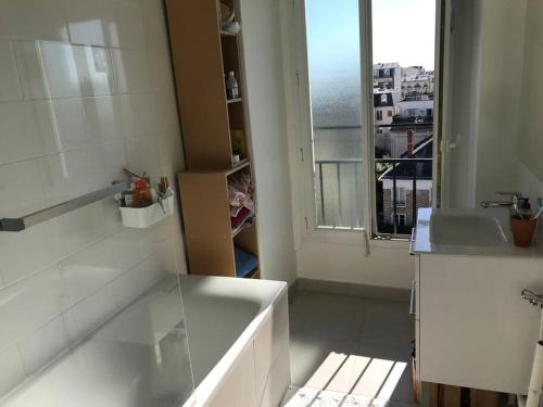 une salle de bain avec une baignoire, un lavabo et une fenêtre dans l'établissement Appartement Haussmanien, lumineux à Paris, à Vincennes