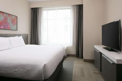 a hotel room with a bed and a flat screen tv at Hilton Garden Inn Iowa City Downtown University in Iowa City