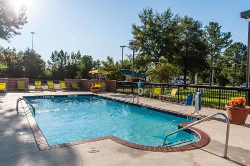a swimming pool at a resort with chairs and trees at Hampton Inn & Suites Jackson Coliseum in Jackson