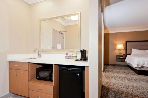 里奇兰Hampton Inn & Suites Ridgeland的带水槽、镜子和床的浴室