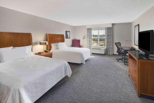 a hotel room with two beds and a flat screen tv at Hilton Garden Inn Jackson-Madison in Madison