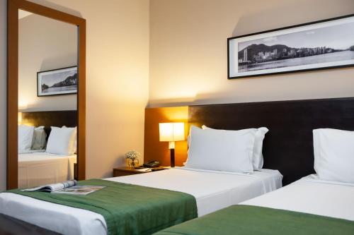 a hotel room with two beds and a mirror at Golden Tulip Porto Vitória in Vitória