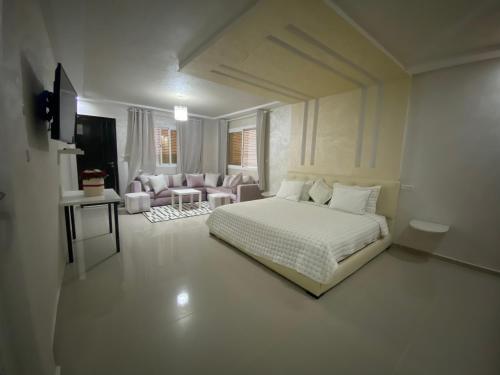 a white bedroom with a bed and a living room at Chambres d hotes Villa 