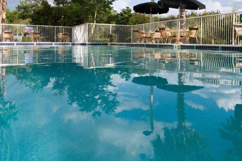 uma piscina de água com cadeiras e um guarda-sol em Hilton Garden Inn Jacksonville Airport em Jacksonville