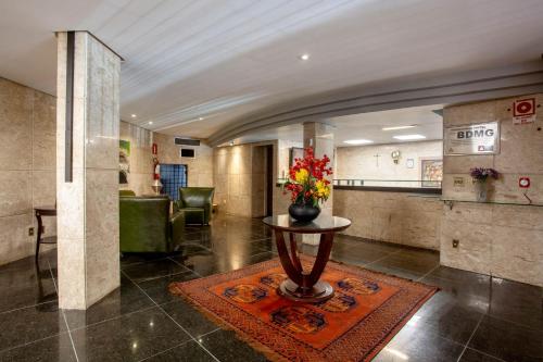 un vestíbulo con una mesa con un jarrón de flores. en Savassinho Hotel & Residence, en Belo Horizonte