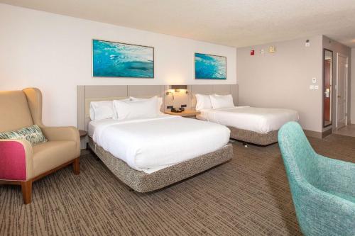um quarto de hotel com duas camas e uma cadeira em Hilton Garden Inn Jacksonville Airport em Jacksonville