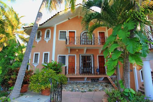 a large orange house with a balcony and palm trees at Hotel Santa Fe in Puerto Escondido