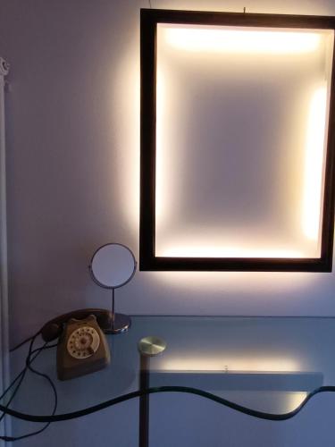 a mirror on a wall with a lamp on a table at AFFITTACAMERE SobborgoSpina47 in Sarzana