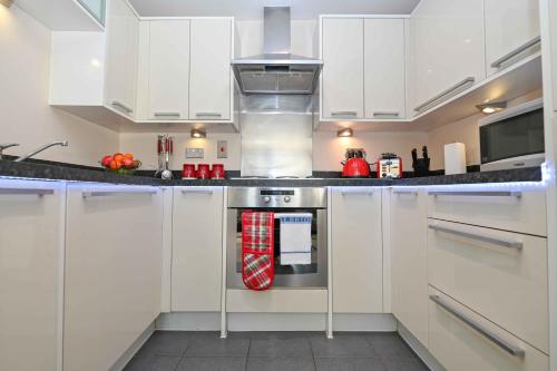 a kitchen with white cabinets and a stove top oven at One Bedroom Apartment TCA-78 in Watford