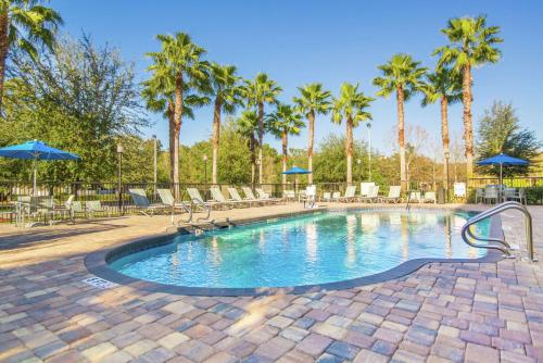 una piscina con palmeras y sombrillas azules en Hampton Inn Jacksonville South/I-95 at JTB, en Jacksonville
