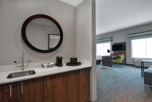 a bathroom with a sink and a mirror and a living room at Hampton Inn & Suites Middleburg, Fl in Middleburg