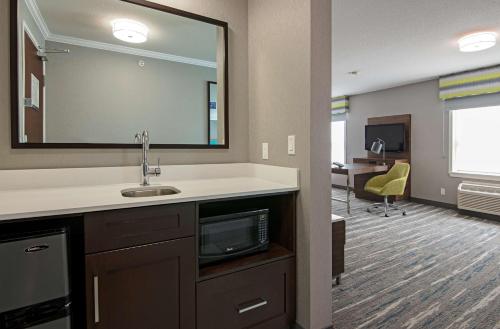 Hampton Inn by Hilton Kamloops في كاملوبس: غرفة مكتب مع حوض ومرآة