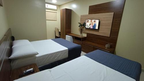 a hotel room with two beds and a tv at Hotel Maxsuel in Cachoeirinha