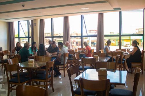 a group of people sitting at tables in a restaurant at Hotel Maxsuel in Cachoeirinha