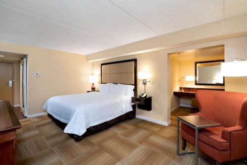 Habitación de hotel con cama y silla en Hampton Inn Lafayette, en Lafayette