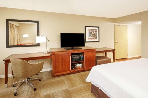 a hotel room with a bed and a desk with a television at Hampton Inn Lafayette in Lafayette