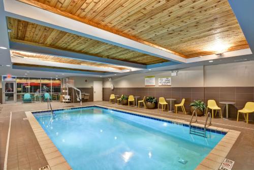 a pool in a hotel lobby with chairs and tables at Home2 Suites By Hilton Lafayette in Lafayette