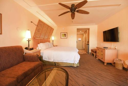 a hotel room with a bed and a couch and a ceiling fan at Hampton Inn Key Largo in Key Largo