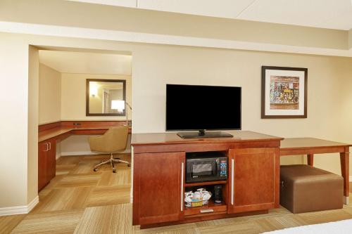a room with a desk with a television and a chair at Hampton Inn Lafayette in Lafayette