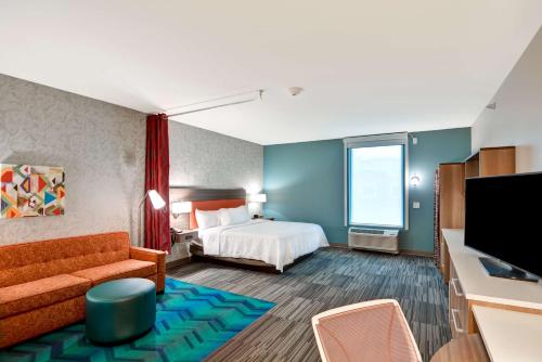 Habitación de hotel con cama y TV de pantalla plana. en Home2 Suites By Hilton Lafayette, en Lafayette