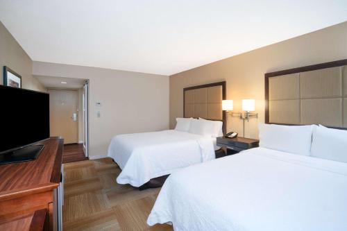 a hotel room with two beds and a flat screen tv at Hampton Inn Lafayette in Lafayette