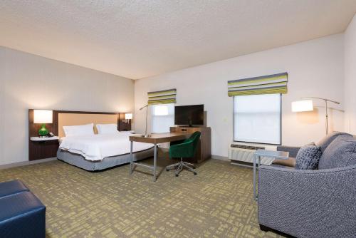 ein Hotelzimmer mit einem Bett und einem Schreibtisch in der Unterkunft Hampton Inn & Suites East Lansing in Okemos