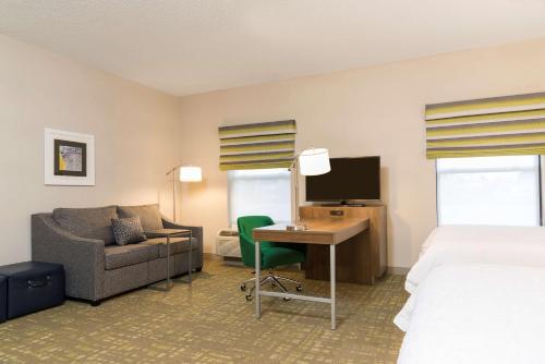a hotel room with a bed and a desk with a computer at Hampton Inn & Suites East Lansing in Okemos