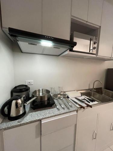 a kitchen with a counter top with pots and pans at Naga City Centro perfect Stay in Naga