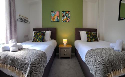 two twin beds in a room with green walls at Emerald House - TV in every bedroom! in Neath