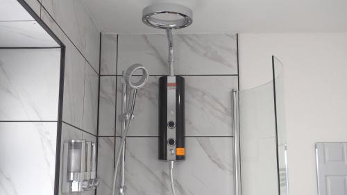 een douche in een badkamer met een glazen deur bij Emerald House - TV in every bedroom! in Neath