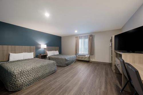 WoodSpring Suites East Lansing - University Area في إيست لانسنغ: غرفة فندقية بسريرين وتلفزيون بشاشة مسطحة