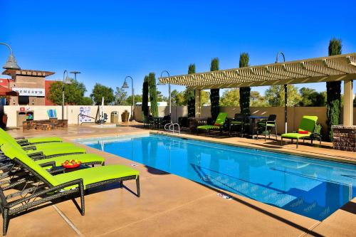 a swimming pool with green lounge chairs and a patio at Hampton Inn & Suites Las Vegas South in Las Vegas