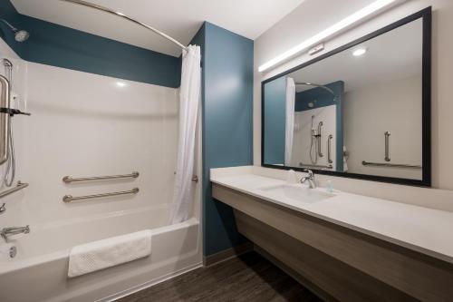 WoodSpring Suites East Lansing - University Area في إيست لانسنغ: حمام مع حوض وحوض ومرآة