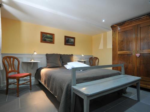 a bedroom with a bed with a bench and two chairs at Gîte Marcel et Marianne jardin et parking privatifs in Ebersheim