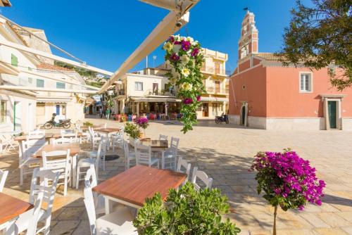 a patio with tables and white chairs and flowers at Flora Maisonettes 2 in Gaios