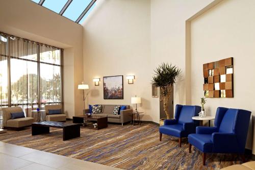 a lobby with a living room with blue chairs and a couch at Embassy Suites Los Angeles - International Airport/North in Los Angeles