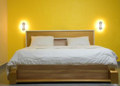 a bed in a room with a yellow wall at HOTEL MAVILLA Cotonou in Cotonou