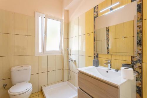 bagno con servizi igienici, lavandino e finestra di Villa Georgia a Vlachata